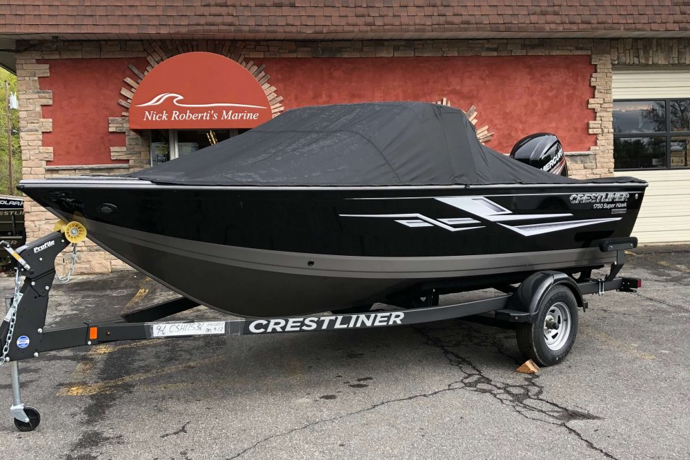 Black boat with a black cover on a trailer